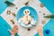 Fun food idea for kids. Christmas children`s Breakfast: snowman of cottage cheese on a blue plate. spoon in child`s hand