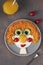 Fun Food for kids - smiling face ginger boy from fried eggs, carrot, cucumbers and cherry tomatoes on gray plate