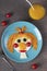 Fun Food for kids - smiling face ginger girl made from fried eggs, carrot, cucumbers and cherry tomatoes on blue plate
