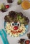 Fun Food for kids - smiling face from pasta, sausages, egg, cherry tomato and lettuce leaves on blue plate