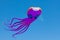 Fun, giant purple octopus kite, 100 feet long, flying under blue sky