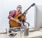 Fun male independent enjoying playing guitar at his computer desk