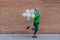Fun portrait of happy energetic mature man holding balloons and running in street , feeling free.