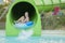 Fun in the sun-pretty girl in bikini comes down water chute in to swimming pool. Beautiful girl riding a water slide. happy woman