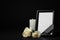 Funeral photo frame with ribbon, white roses and candle on dark table against black background