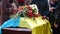 Funerary urn with ashes of dead and flowers at funeral. Burial urn decorated with flowers and people mourning in