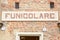 Funicular station entrance sign in red bricks wall in a sunny day in Mondovi, Italy