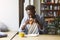 Funky African American guy having breakfast in cafe, eating tasty croissant with coffee