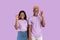 Funky black guy and his girlfriend showing okay gesture over lilac studio background