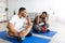 Funky black guy and his girlfriend taking break after domestic training, holding water bottles, staying hydrated at home