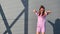 Funky woman in summer bright clothes smiling dancing at metallic wall. Shot with RED camera in 4K