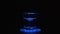 Funnel of water is spinning in the glass. Slow motion in blue light on black background, close-up