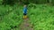 Funny active toddler baby boy running along a path and then turns to parents. Green forest background. Cute kid in blue