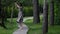 funny adult lady is walking alone in park at summer day, playing with tree and strolling