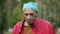 Funny African American young man smudging face with black dirty soil looking at camera with serious facial expression