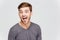 Funny amusing young man in grey pullover screaming