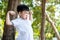 Funny Asia kid. Ugly grimace 7 years old boy with white t-shirt standing in the garden with copy space. closeup portrait. Boy