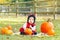 funny Asian Chinese baby girl in ladybug costume sitting in autumn fall park outdoor with yellow orange pumpkins