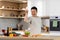 Funny asian man salting food, kitchen interior