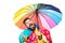 Funny autumn man in raincoat under umbrella is trying to see if there is rain. Men with rainbow-colored umbrella