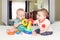 Funny baby boys sitting together on bed playing stacking rings toy