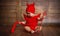 Funny baby in devil halloween costume on wooden background