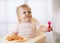 Funny baby eating noodle. Grimy kid girl eats spaghetti with fork sitting on table at home