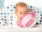 Funny baby is eating from pink plate