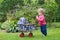 Funny baby girl with vintage doll stroller in garden