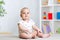 Funny baby kid girl sitting on floor in children room