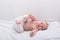 Funny baby lying down on white sheet. Newborn lying on side and smiling