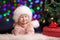 Funny baby in Santa Claus hat on bright festive ba