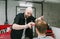 Funny bald barber make a stylish hairstyle for a young man and looks curiously into the camera. Funny barber clipping client with
