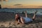 Funny bald man with red beard posing on the beach at sunset. A humorous male parody of a glamorous girl.