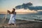 Funny bald man with red beard posing on the beach at sunset. A humorous male parody of a glamorous girl.