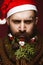 Funny bearded man in a New Year`s image as Santa Claus with decorations on his beard. Feast of Christmas.