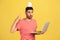 Funny bearded man in striped t-shirt pointing at paper house on his head standing and holding laptop, working from home, freelance