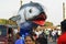Funny big platform with shark fish opens jaws on the crowded street during the traditional Goa carnival