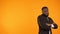 Funny black guy in formalwear dancing, isolated on orange background, template