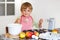 Funny blond kid boy baking apple cake indoors