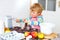 Funny blond kid boy baking apple cake indoors