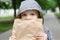 Funny blondheared toddler eating georgian bread with appetite on the street.Holding its in the paper craft package. Closeup