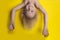 Funny boy with blond hair hanging upside down on yellow background. Boy Mowgli