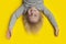 Funny boy with blond hair hanging upside down. Yellow background. Happy boy
