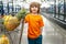 Funny boy with shopping cart full of fresh organic vegetables and fruits standing in grocery department of food store or