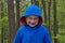 Funny boy in the woods,cheerful boy in the woods alone in a blue jacket