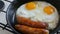 Funny breakfast in the pan in the form of a face and a smile with eyes. Two fried eggs and thick Bavarian sausages fried