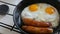 Funny breakfast in the pan in the form of a face and a smile with eyes. Two fried eggs and thick Bavarian sausages fried