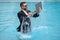 Funny business man in business suit with laptop jumping in splash water in the pool. Remote work. Crazy freelancer