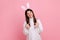 Funny carefree young adult brunette woman with bunny ears, looking playful happy, childish behavior.